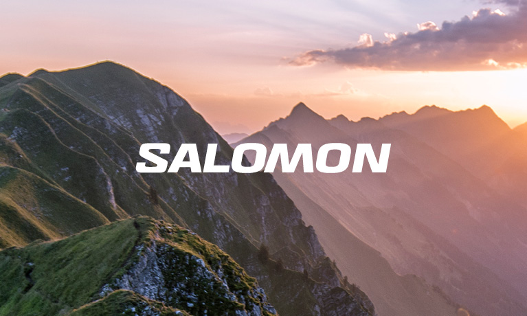 group of hikers in salomon gear walking up a mountain with the salomon logo on the left